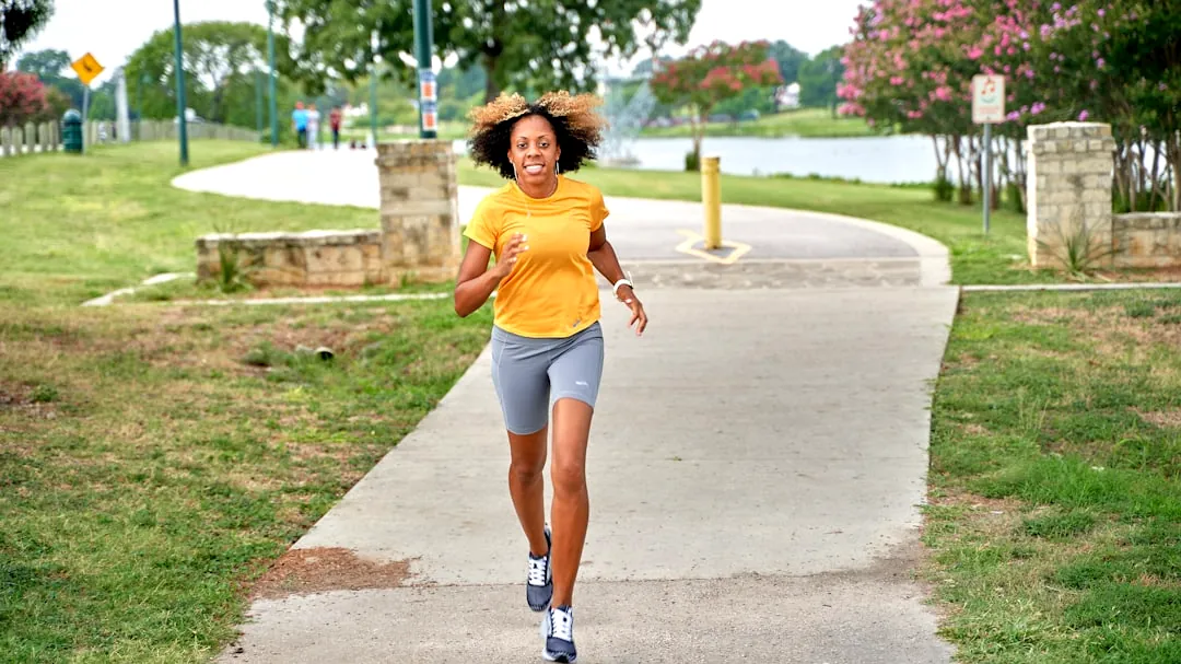 a woman running down a sidewalk in a park