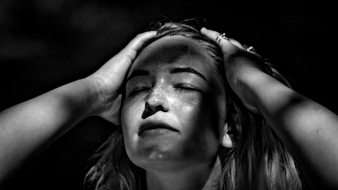 grayscale photography of woman holding her head