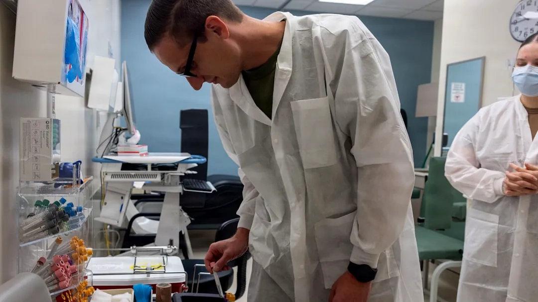 Scientist in lab coat examines sample in laboratory.