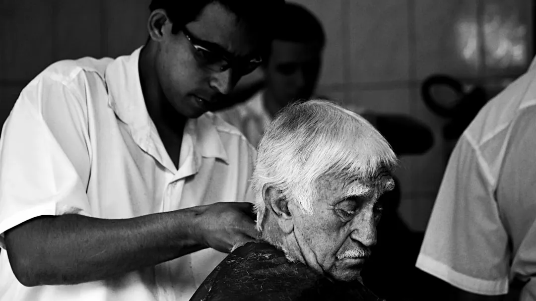 a black and white photo of a man getting his hair cut