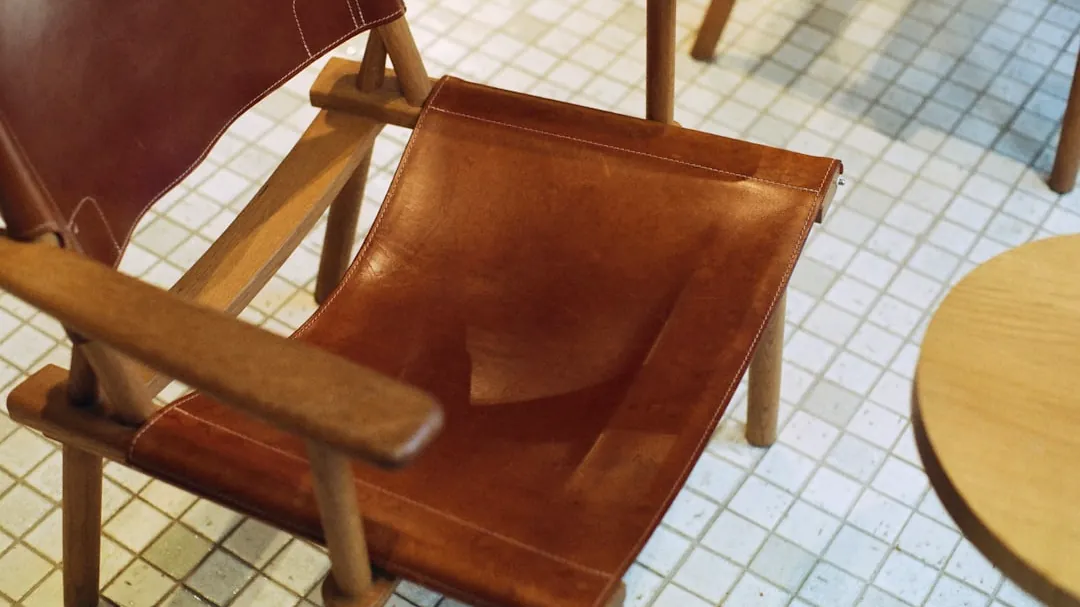 a brown leather chair sitting on top of a tiled floor