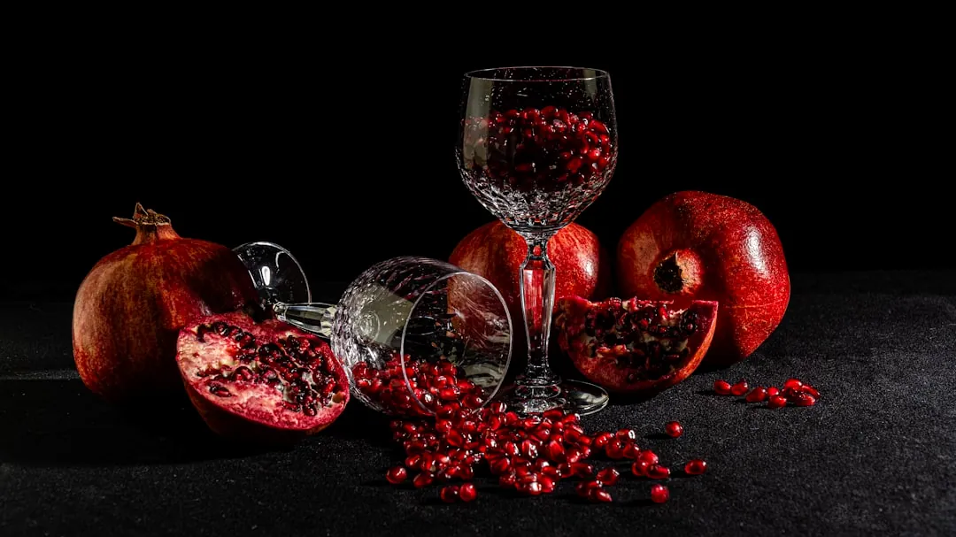 A glass of wine and some pomegranates on a table