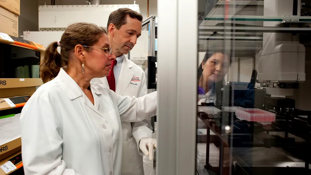 a man and a woman in lab coats looking at something in a cabinet