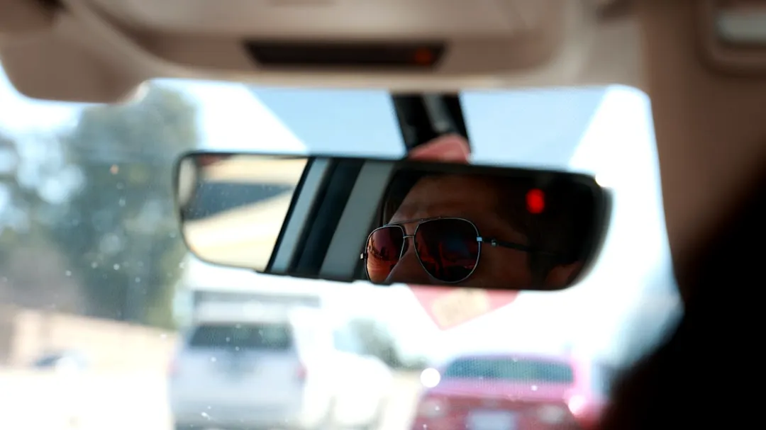 a man in sunglasses is seen in the rear view mirror of a car