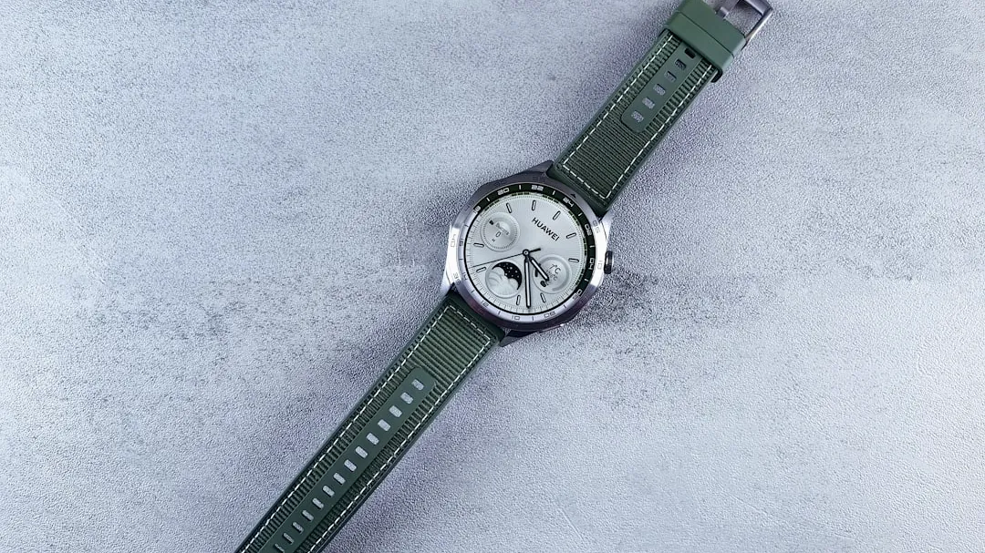 A wristwatch with a green strap on a textured surface.