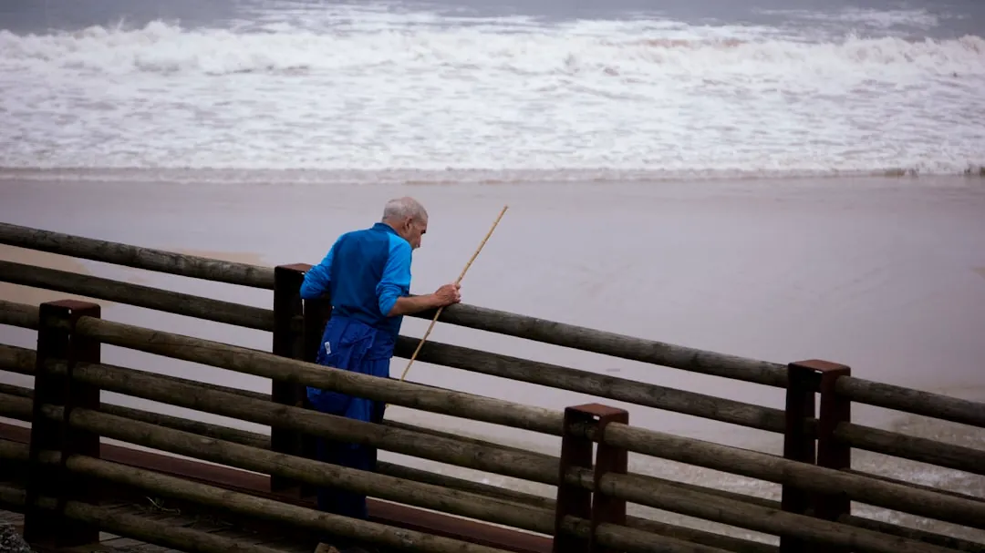 Elderly man with a fishing rod on a wooden boardwalk