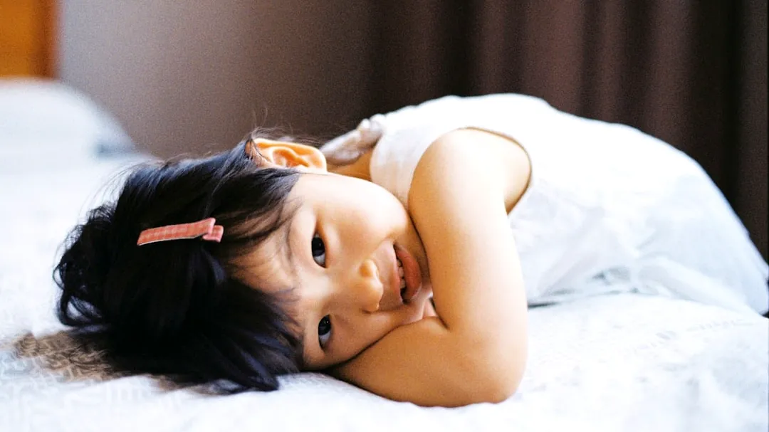 girl in white tank top lying on bed