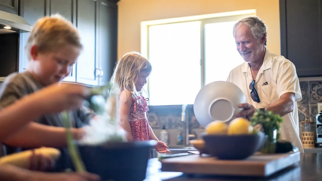 Grandfather and grandchildren prepare food in kitchen
