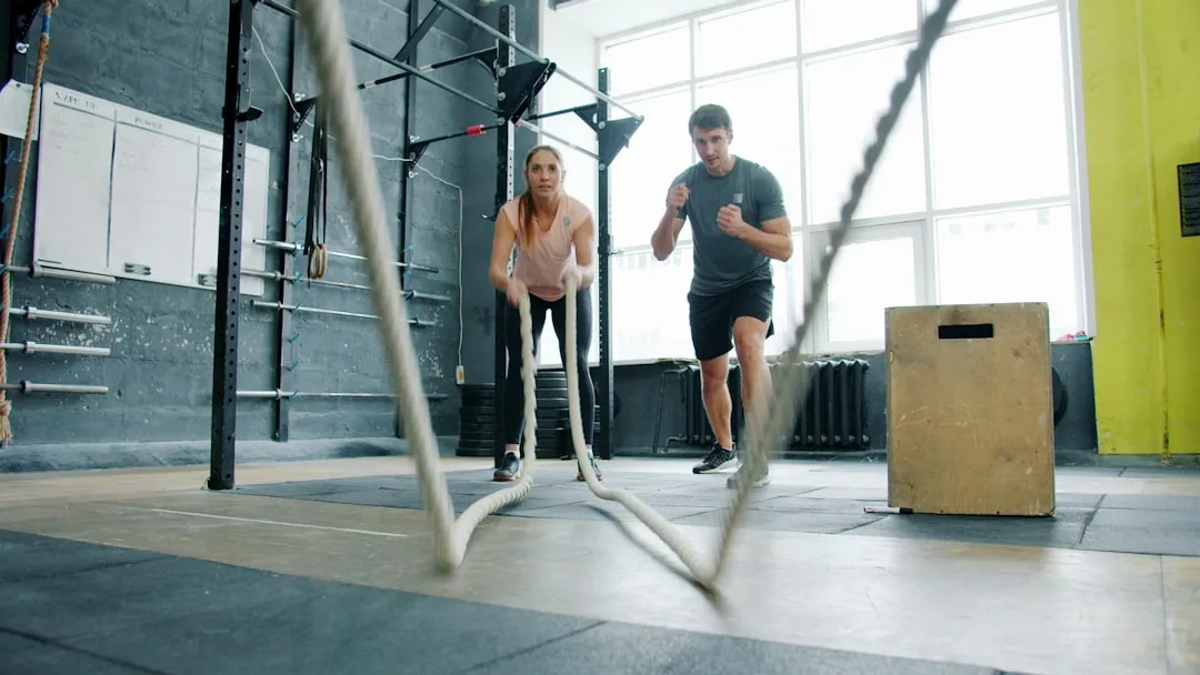 Man and woman exercising with battle ropes.