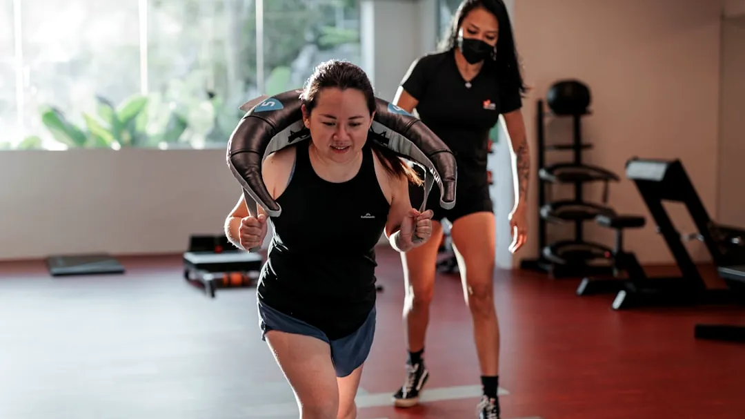 Woman lunging with weight while trainer supervises