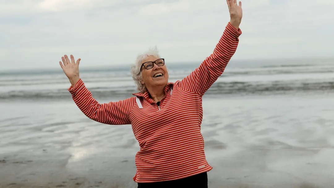 Woman raises arms on the beach with joy.