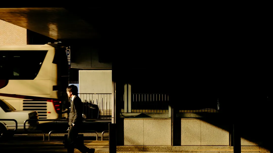 A man walks past a bus at night.