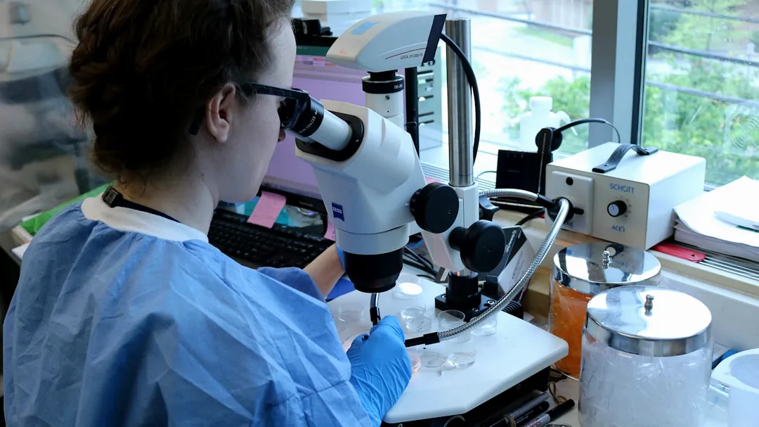 a woman in a lab coat looking through a microscope
