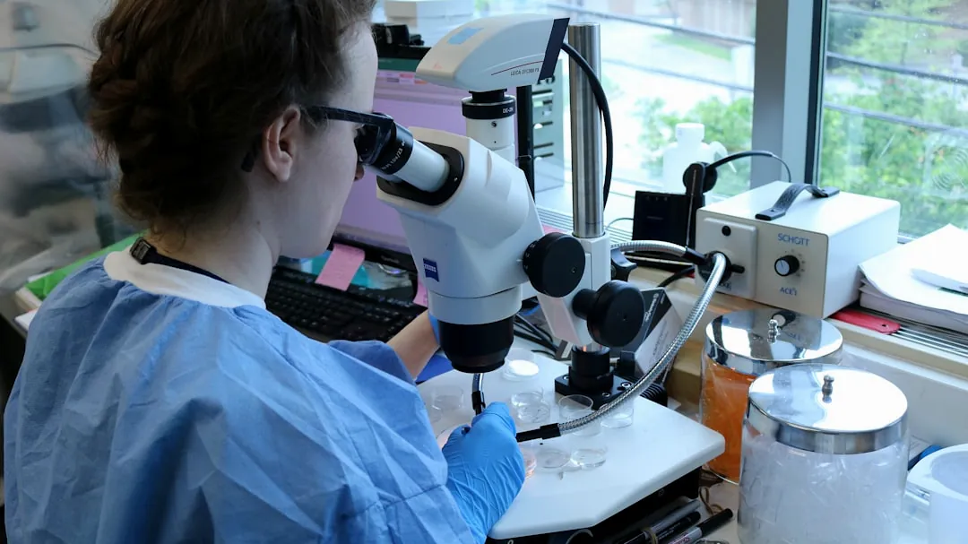 a woman in a lab coat looking through a microscope